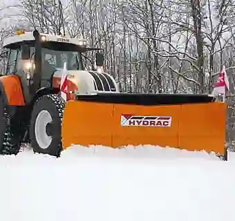 Bild eines orangenen Schneeschildes an einem Steyr Traktor