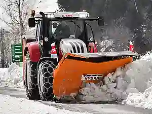 Oranges Hydrac Schneeschild an einem Steyr Traktor montiert