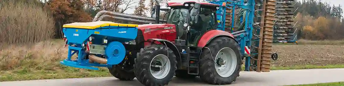 Bild eines roten Case Traktor mit blauem Mähgerät