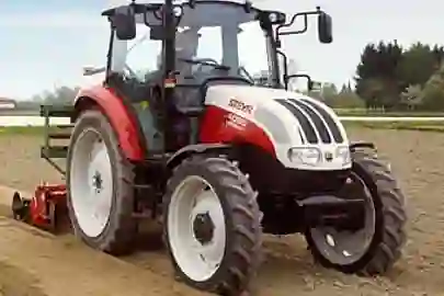 Weiß-roter Steyr Traktor mit Ackerpflug 